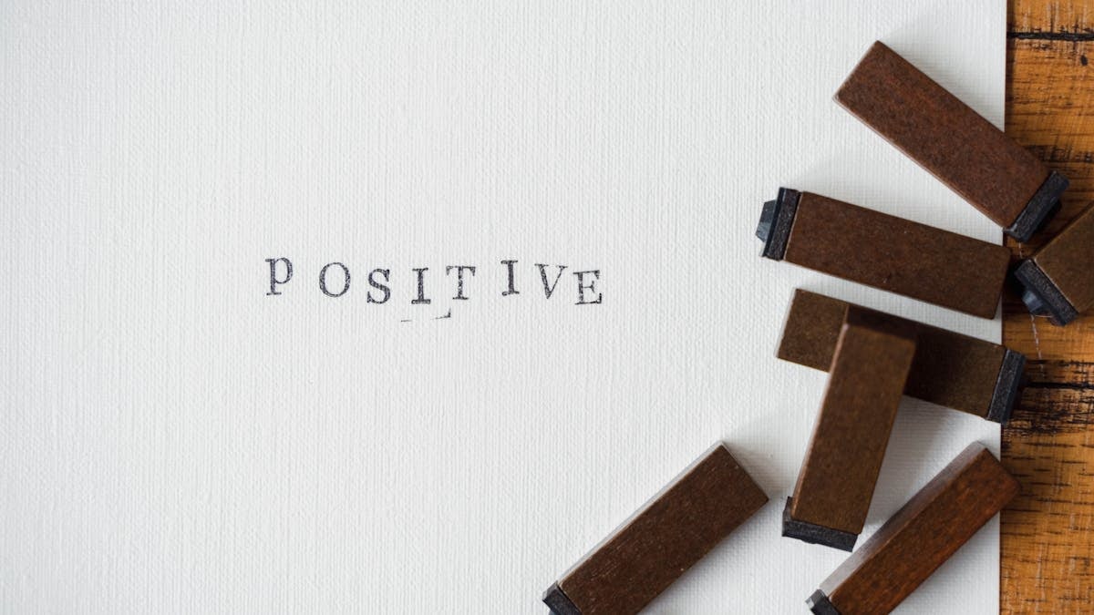 Close-up of 'Positive' word created with vintage wooden letter stamps on textured paper.